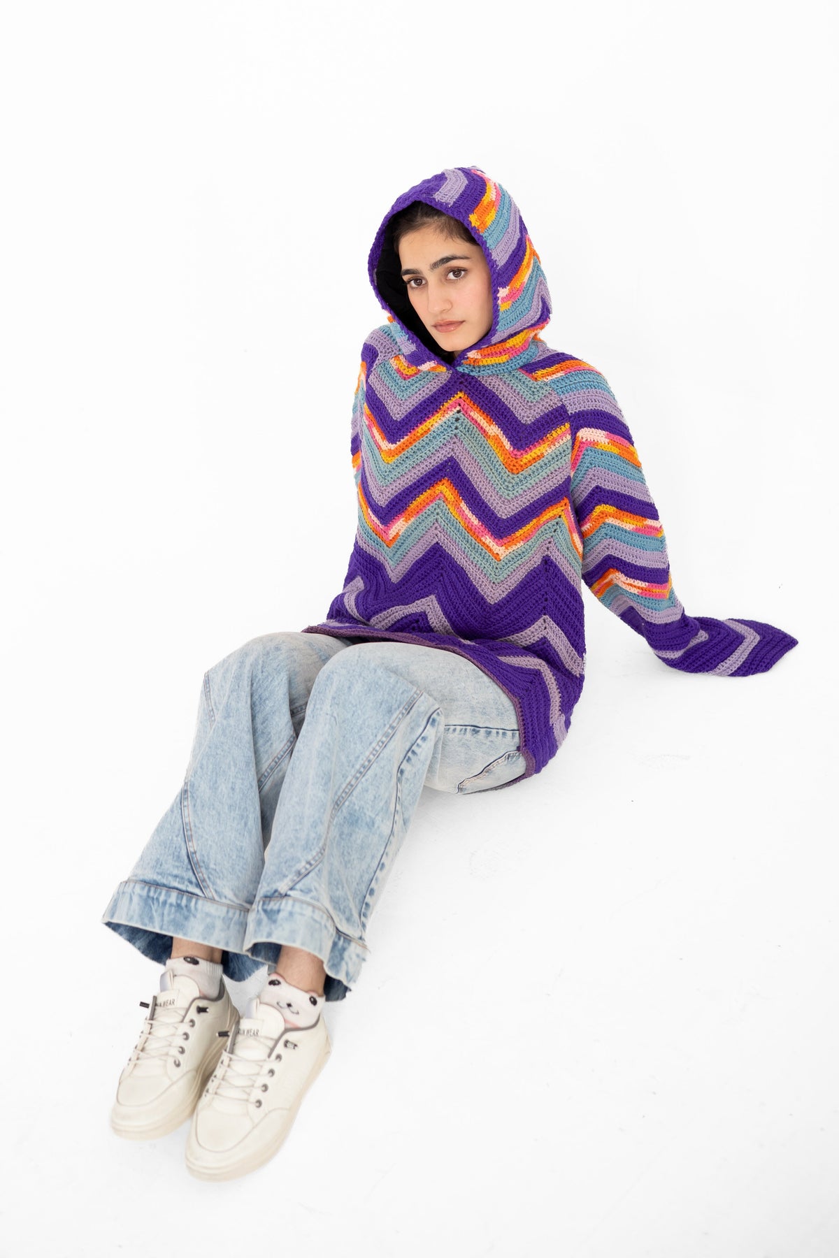 Model seated with hood up in Violet Voltage purple multicolour chevron crochet hoodie – POSHERI
