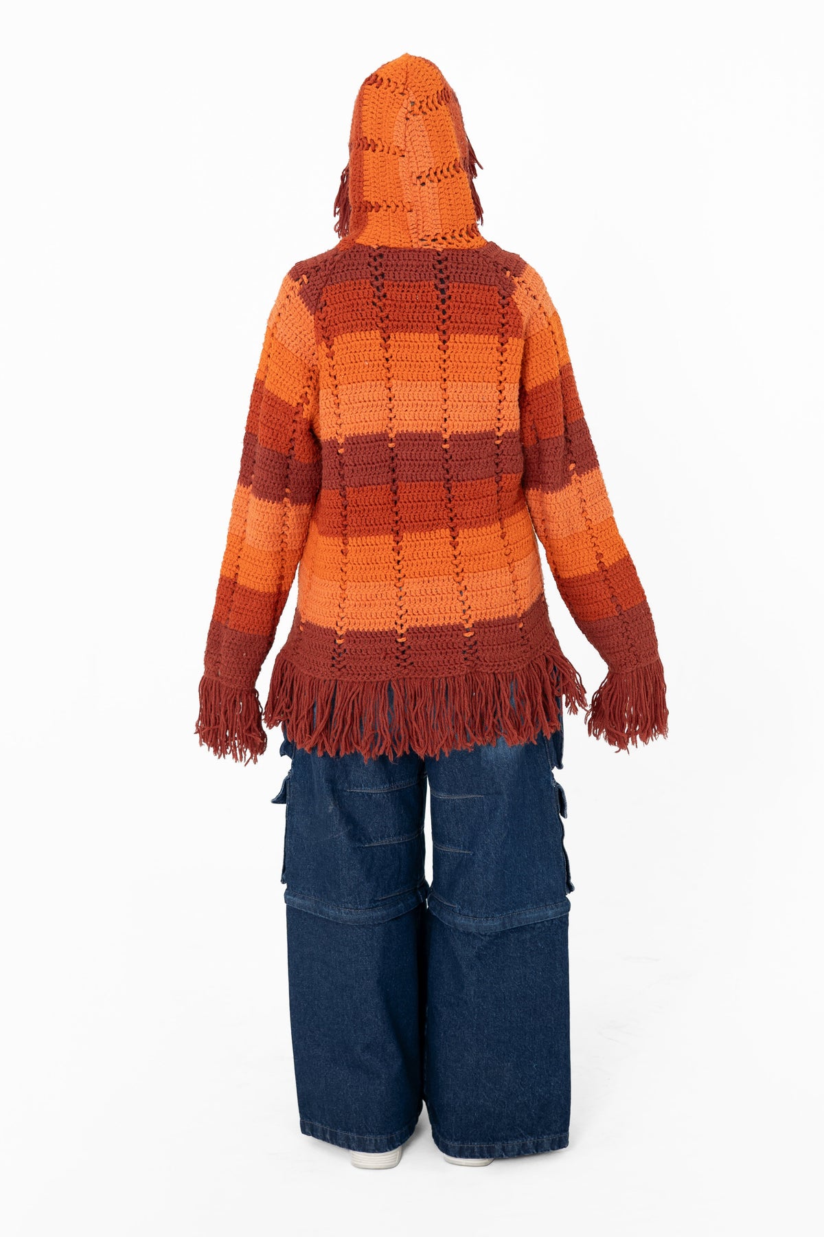 Afterglow crochet hoodie, back view with the fringed hood up and orange and rust stripes