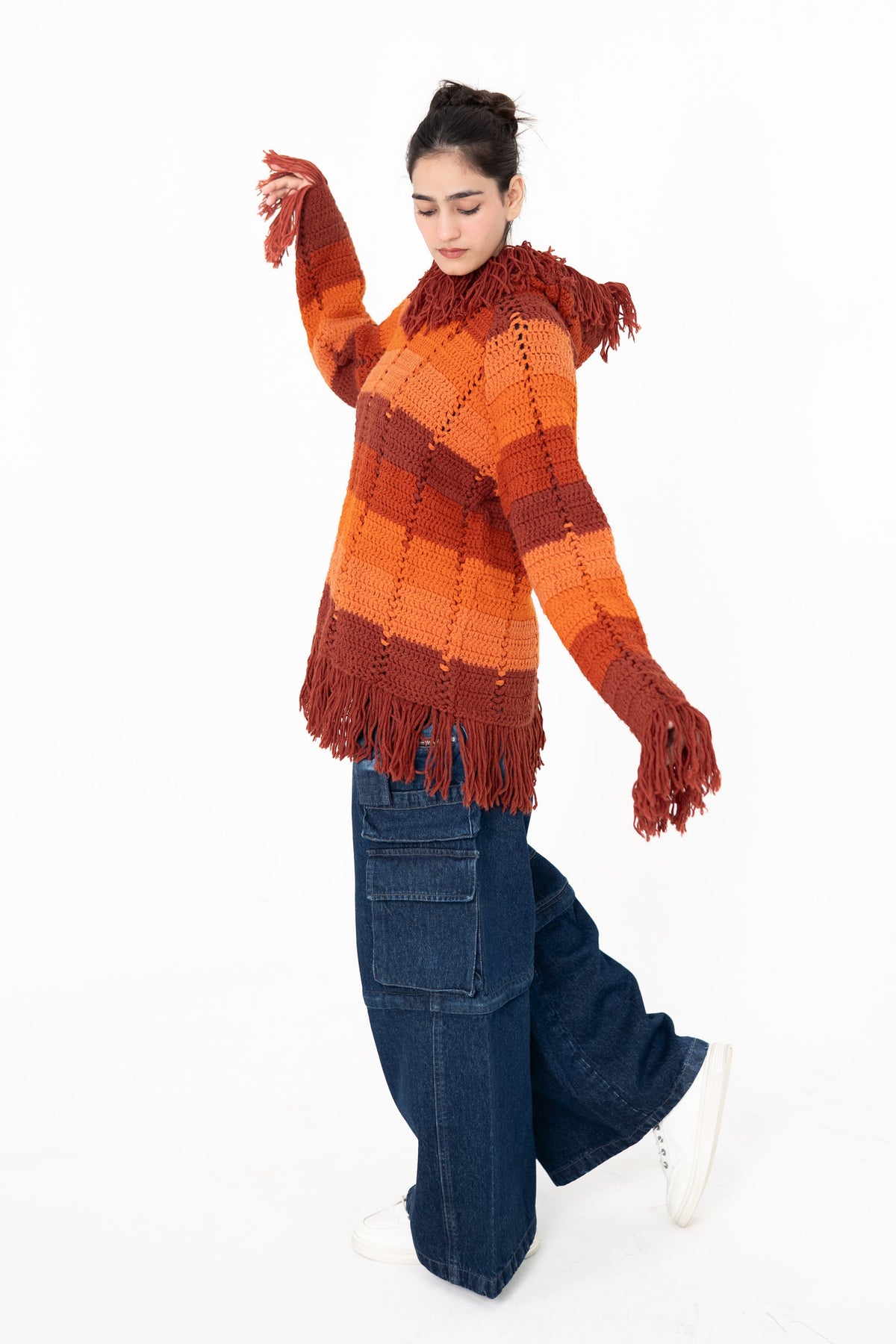 Afterglow orange, terracotta and rust striped handmade crochet hoodie by Posheri, front view with fringed cuffs and hem, styled with wide-leg cargo denim