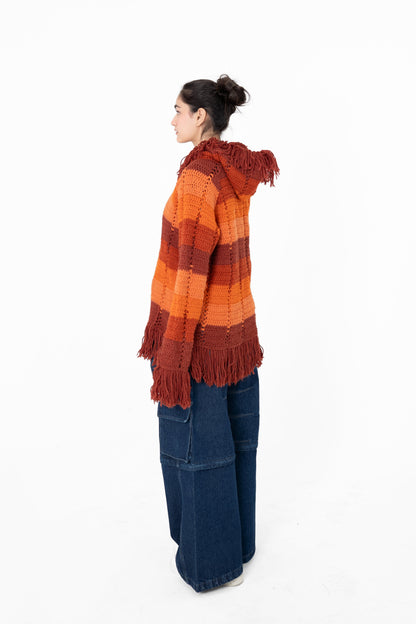 Afterglow orange and rust crochet hoodie, side view showing the relaxed fit and fringed sleeve