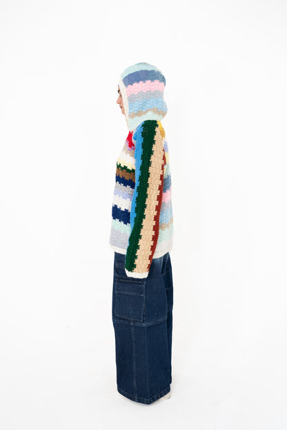 Colour Out Loud multicolour crochet hoodie, side view with the hood up and green, beige and rust striped sleeve