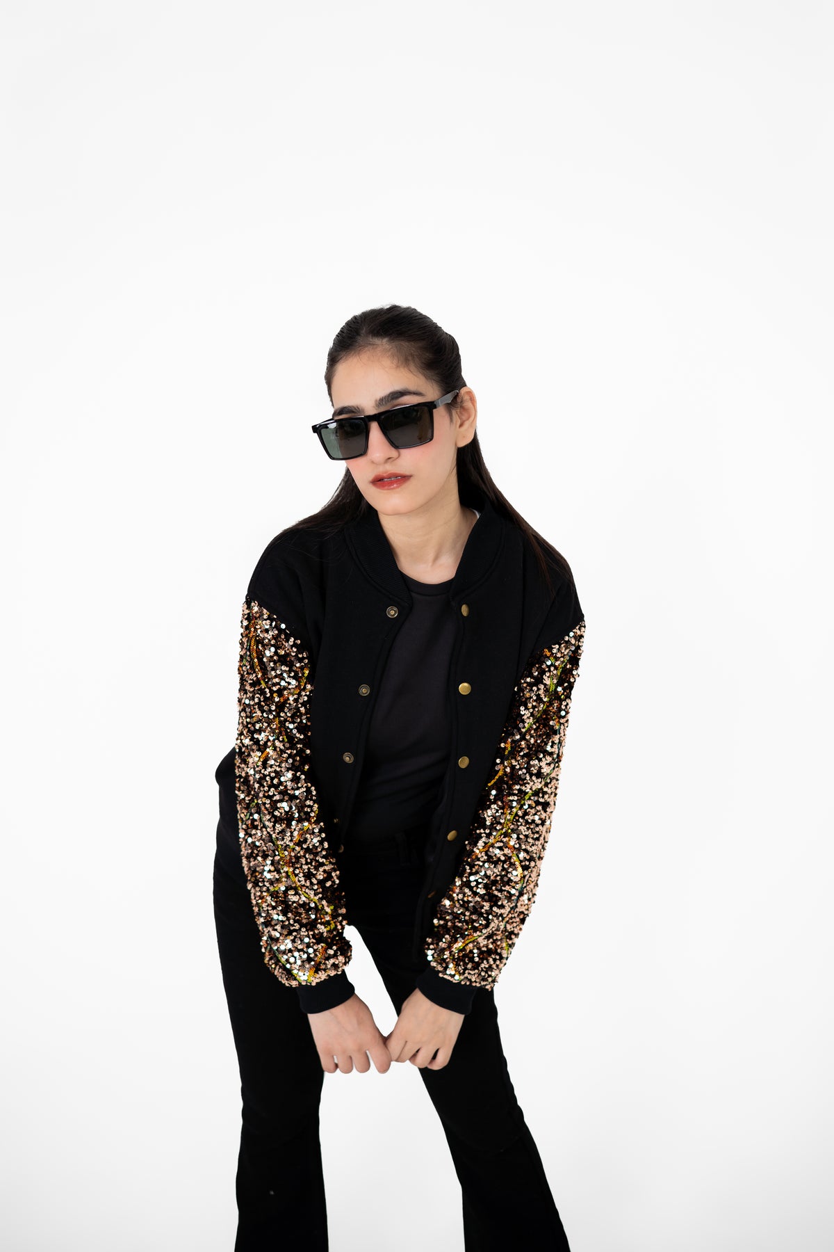 Model posing in Gilt Trip black varsity jacket with bronze-gold sequinned sleeves – POSHERI Outer Control