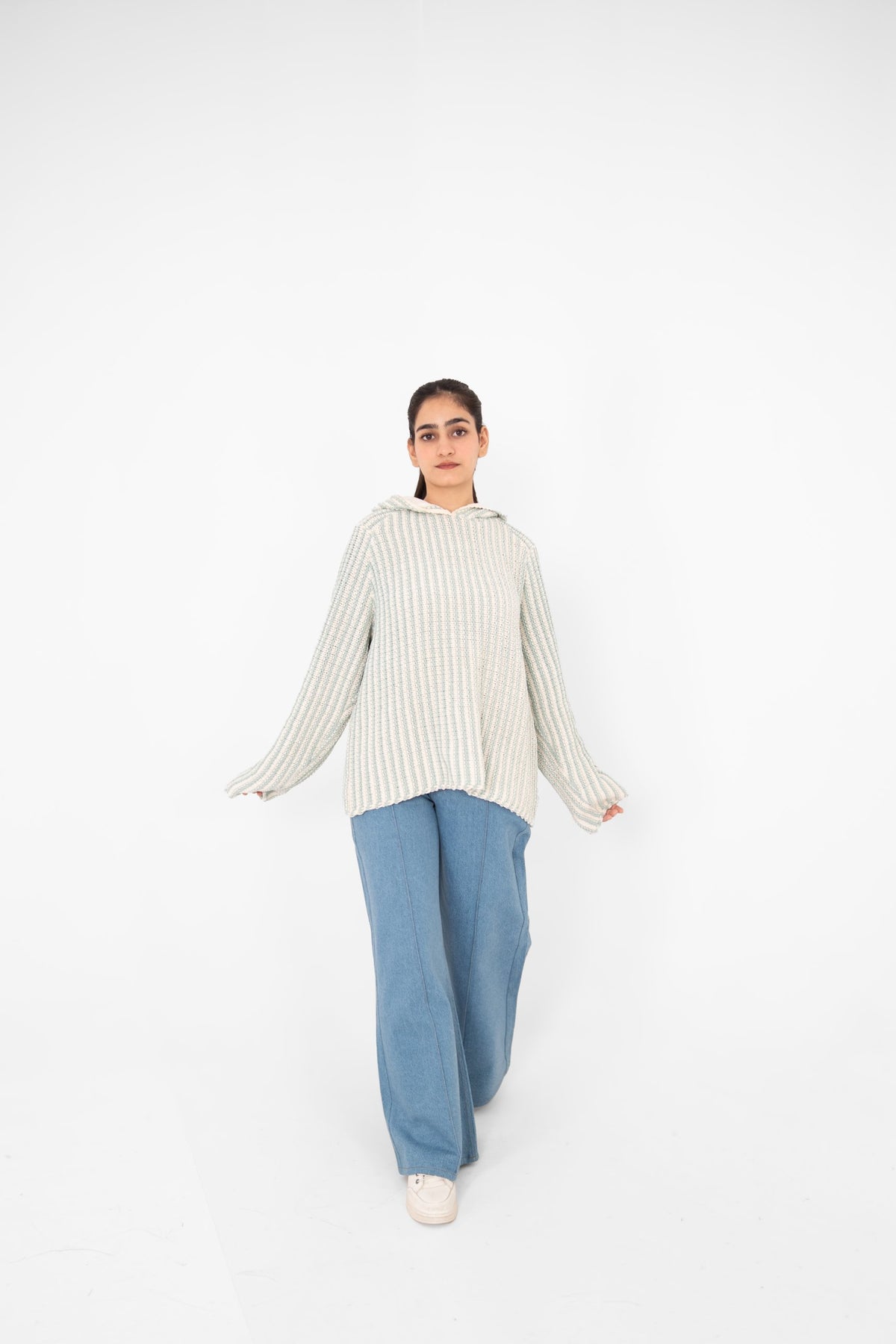 Mint Condition relaxed-fit crochet hoodie with flared sleeves, model walking in light blue wide-leg jeans