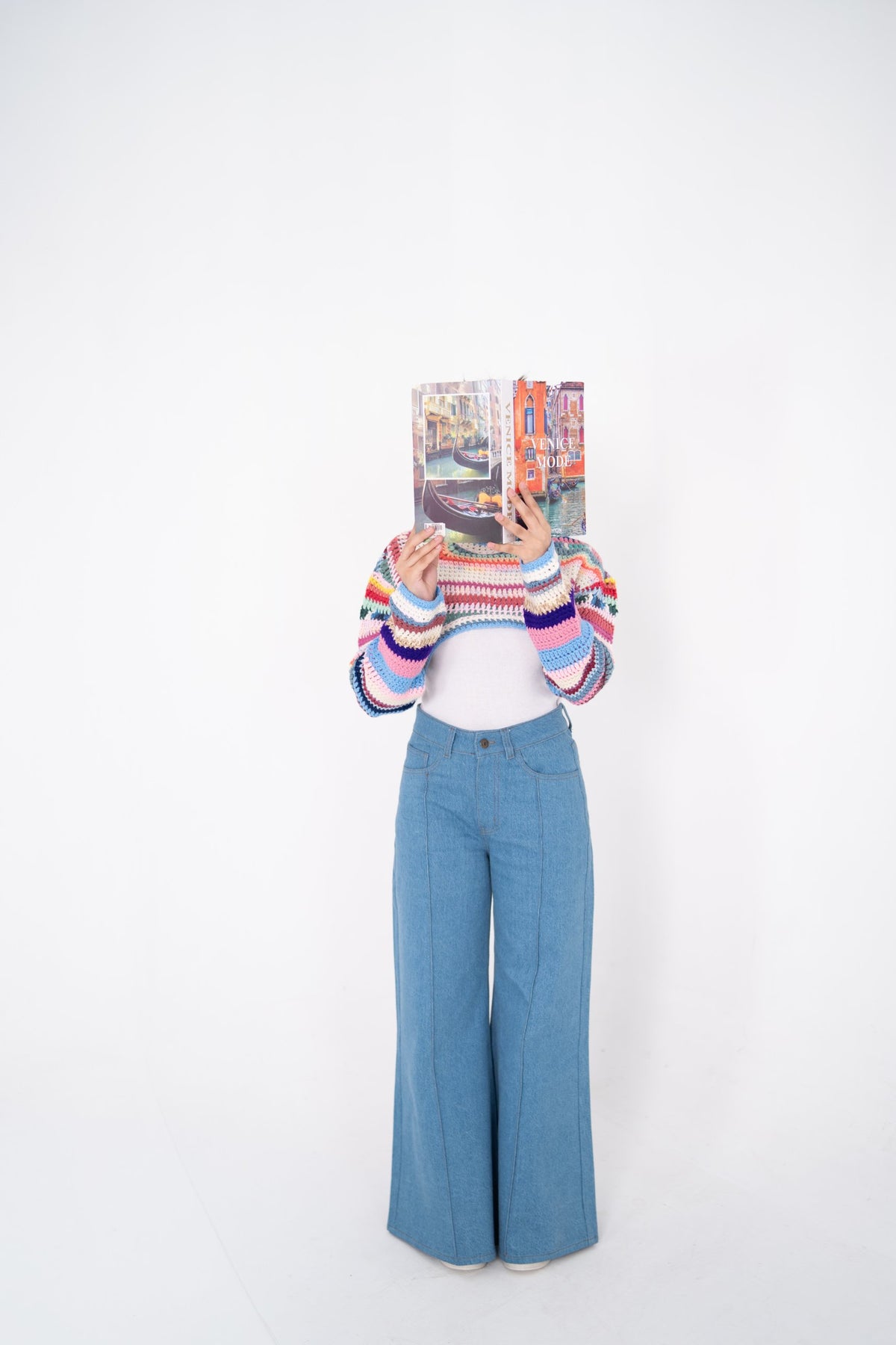 Short Circuit cropped crochet top front view, model holding a book in front of her face