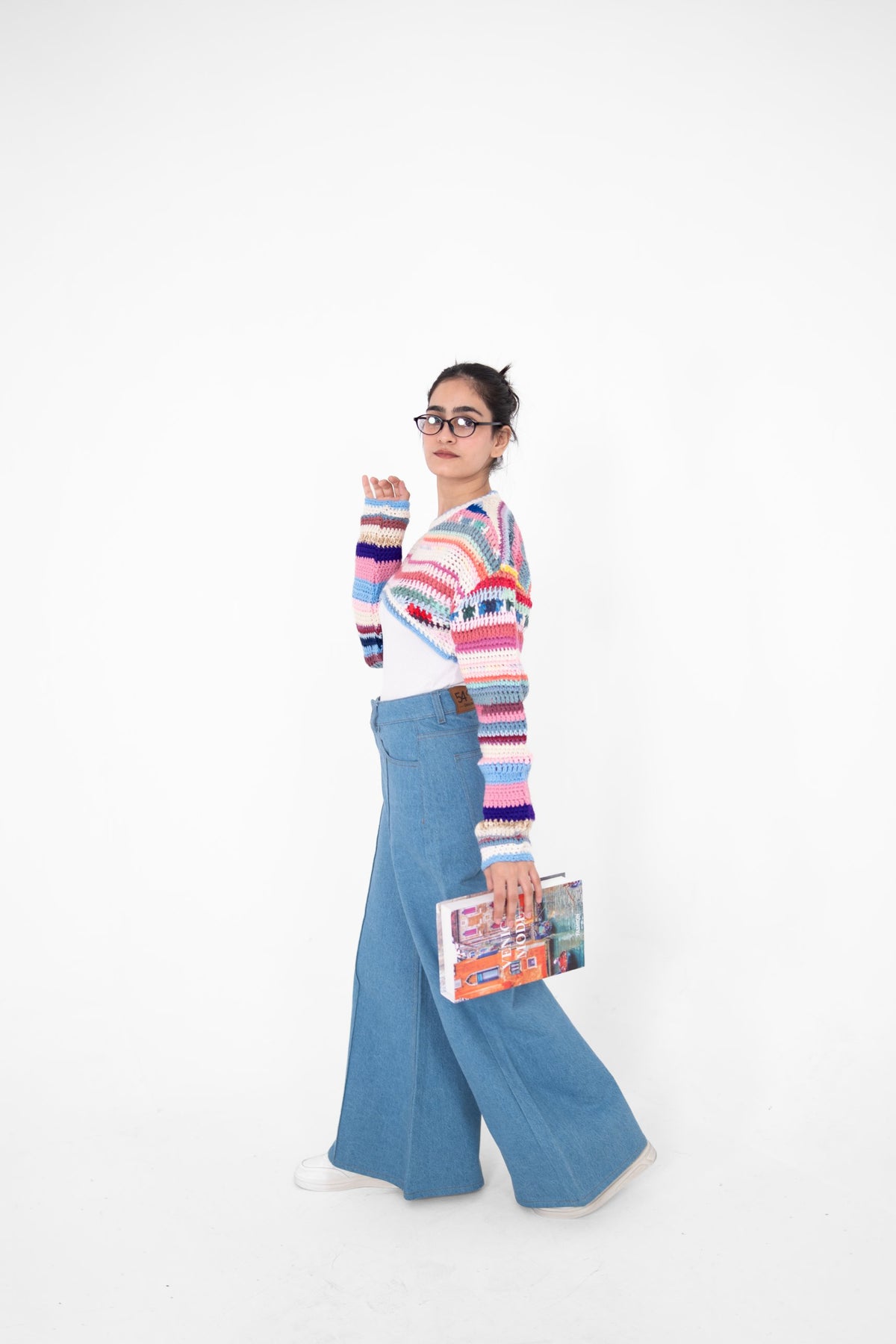 Short Circuit multicolour cropped crochet top with extended sleeves, model walking in light blue wide-leg jeans
